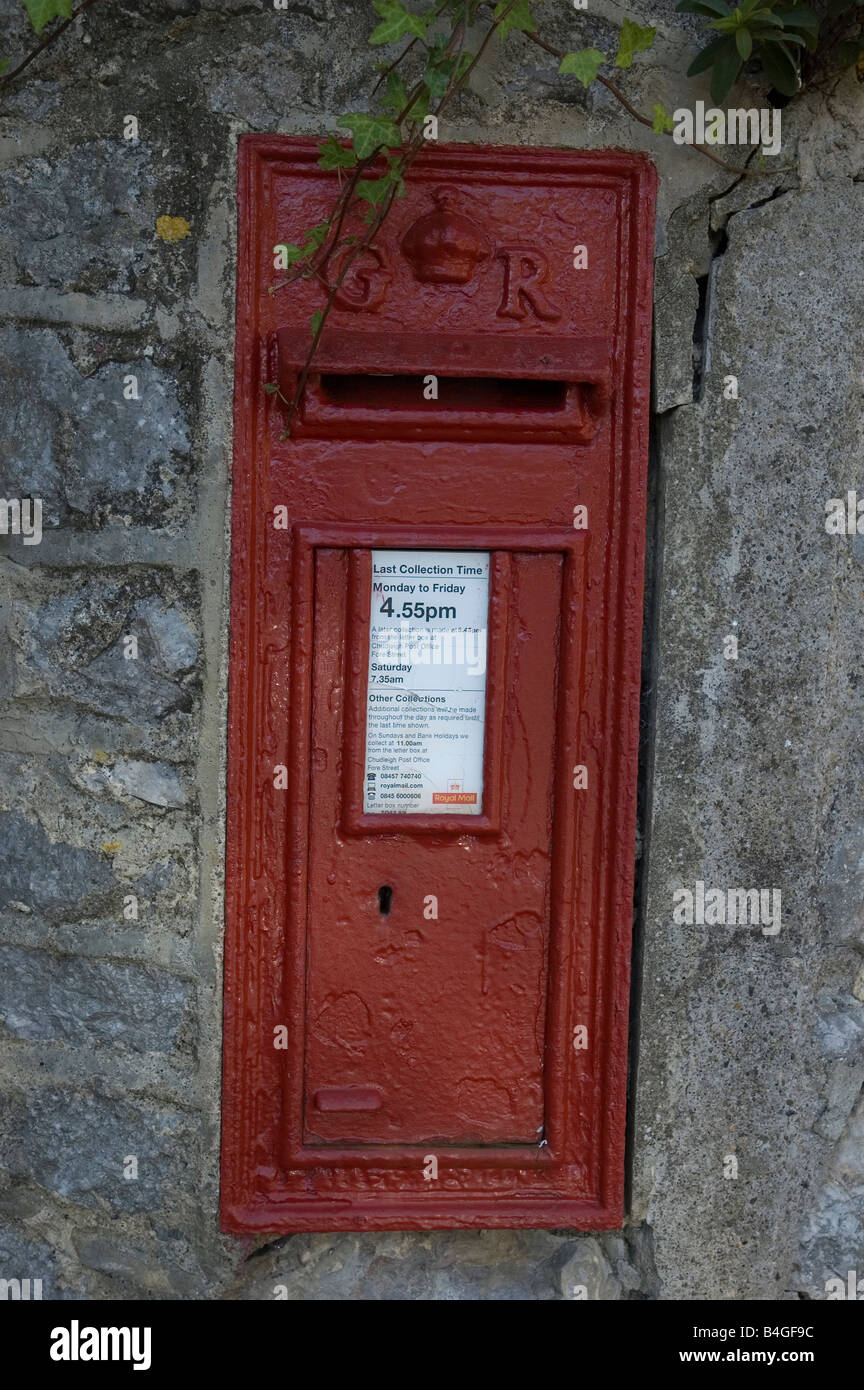 Historic red post box built into a stone wall in Devon, south west England Stock Photo