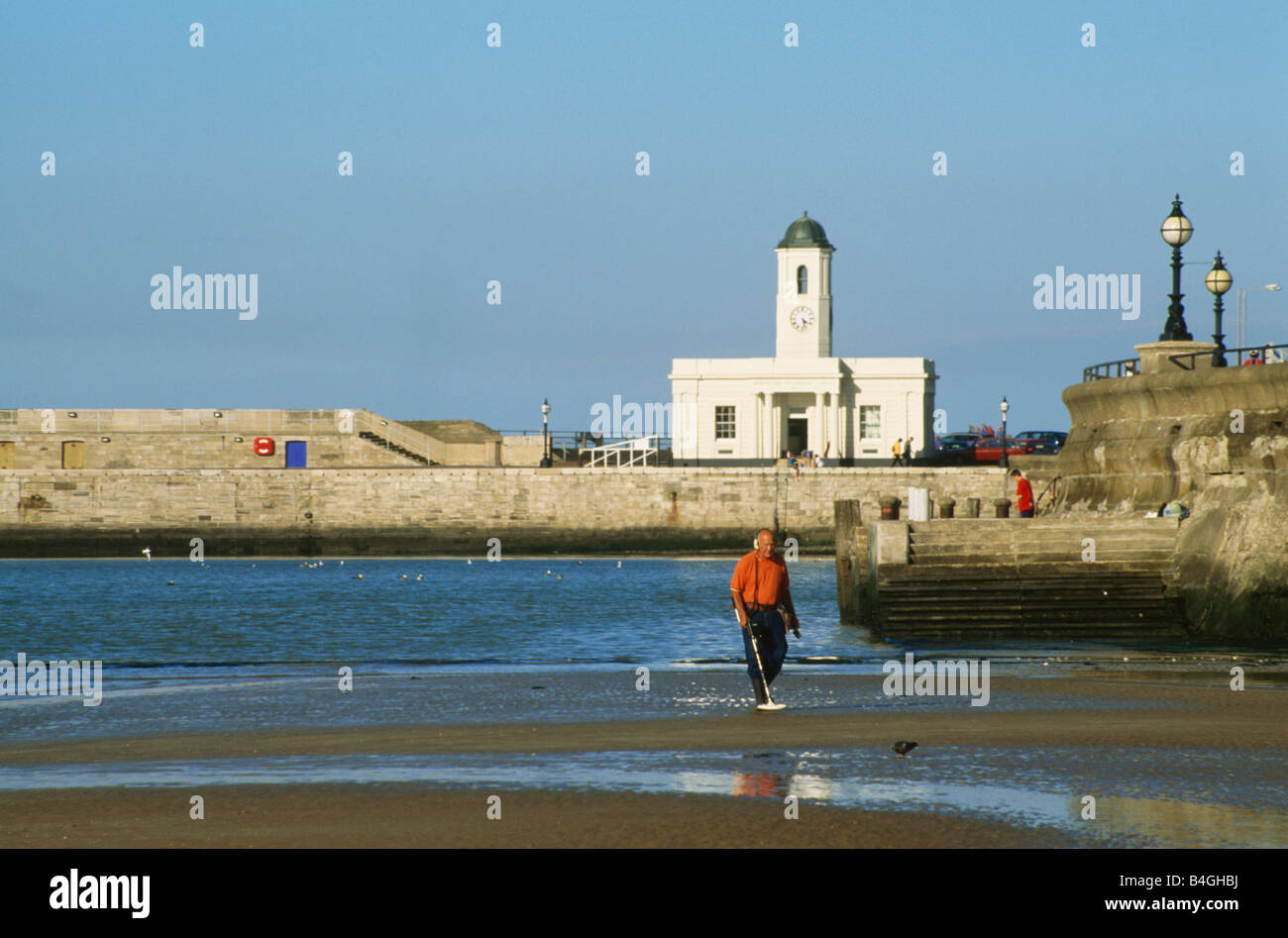 Man using a metal detector at the waters edge in the harbour at Margate ...