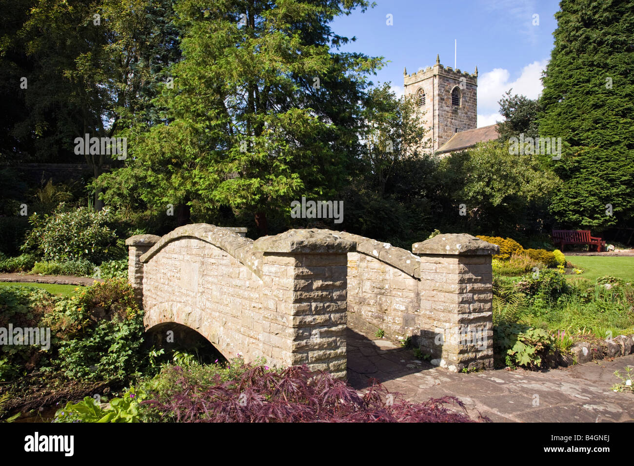 Bridge in Coronation gardens in the village of Waddington Lancashire with St Helens Church in background Stock Photo