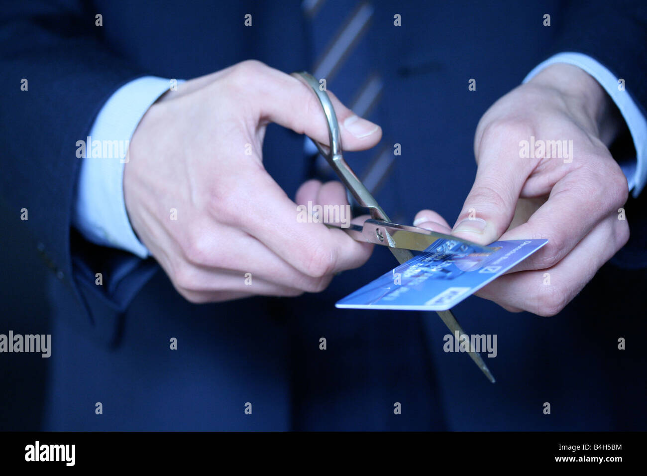 Midsection view of businessman cutting credit card with scissors Stock Photo