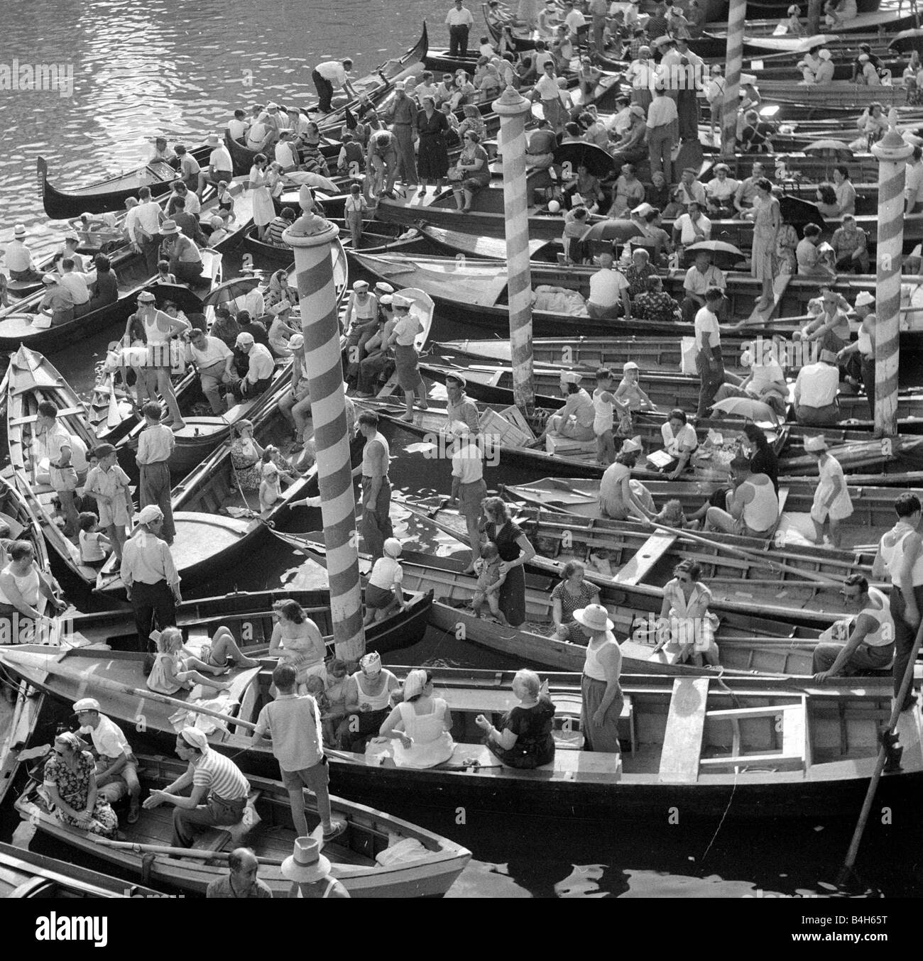 Boats and gondolas tied up as the procession of gondolas pass along the Grand Canal Venice September 1952 Mirrorpix Stock Photo