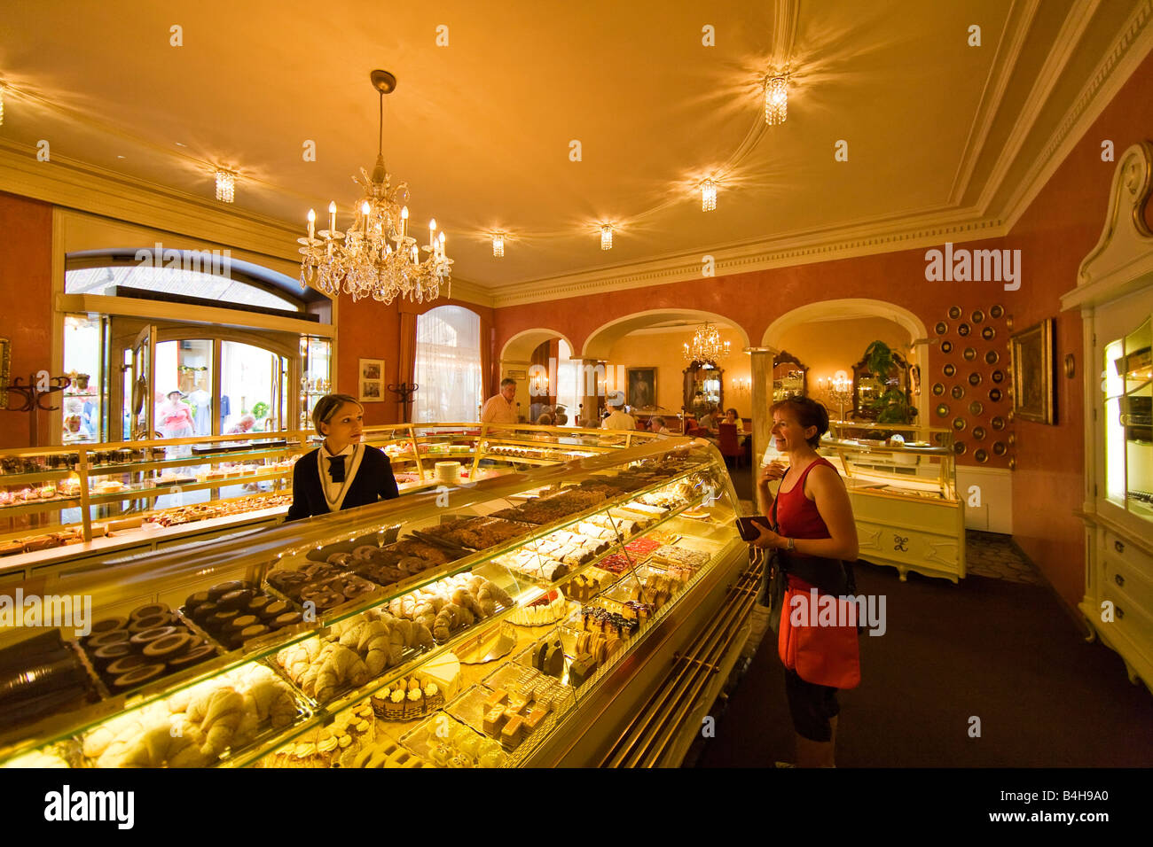 Woman talking to sales clerk at pastry shop counter, Salzkammergut, Upper Austria, Austria Stock Photo