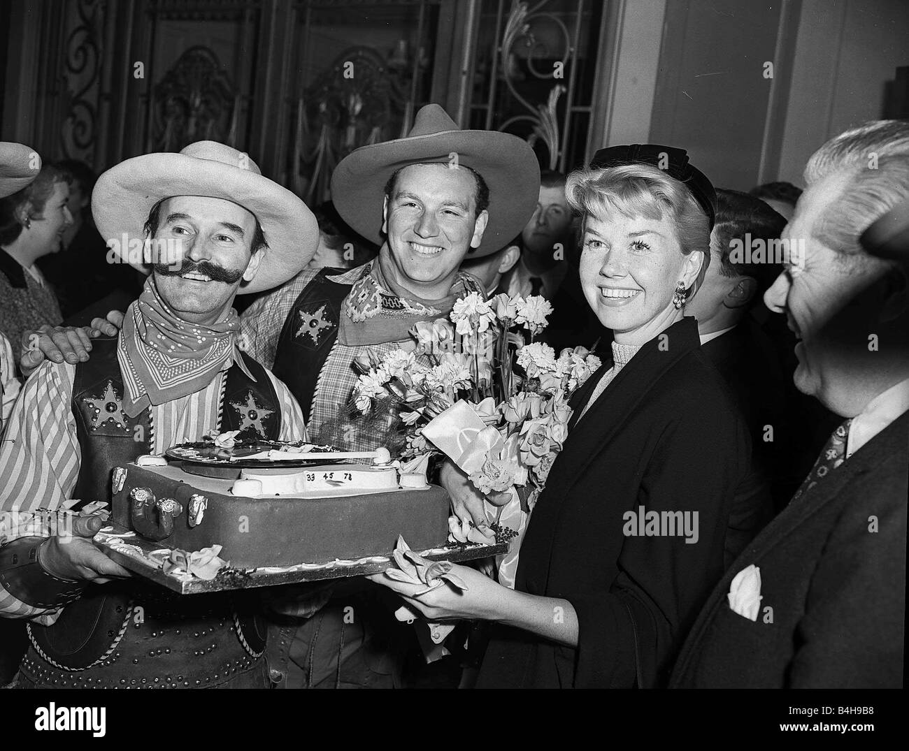 Actress Doris Day is presented with a cake by a couple of cowboys April 1955 Stock Photo