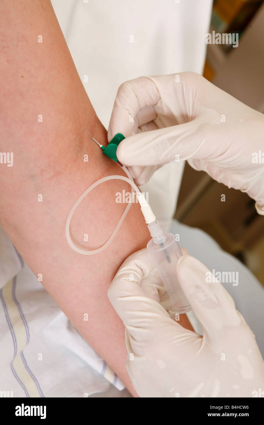 Close-up of person's hands inserting needle on patient's arm Stock Photo