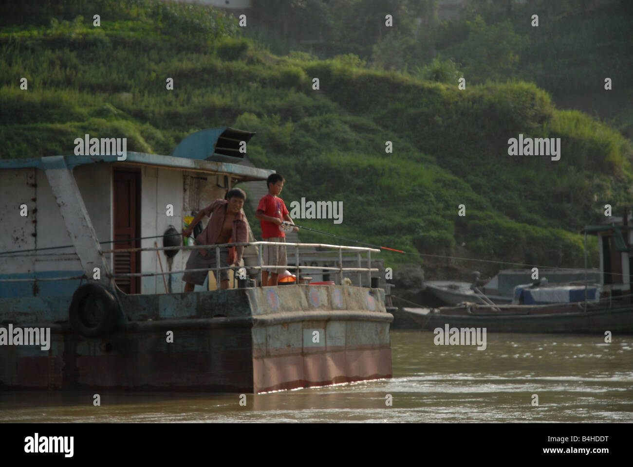 A boy and his father fish of a boat along the Wu River in rural