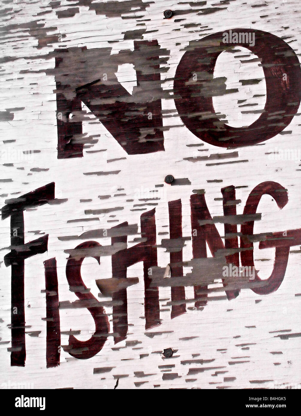 Closeup of an old vintage sign by a lake that reads NO FISHING Stock Photo