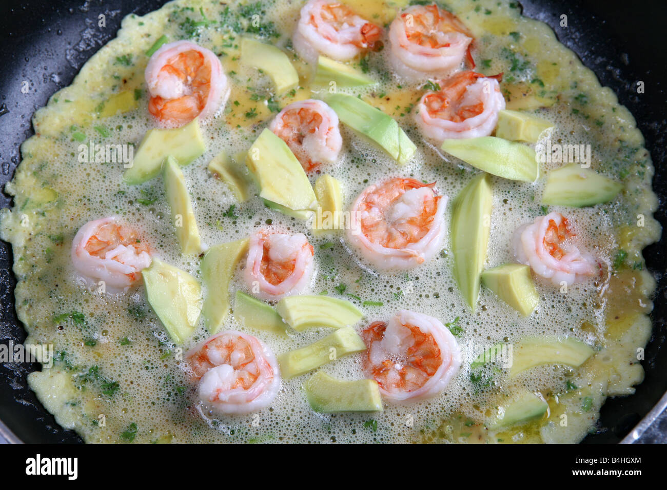 A 'California omlette' with parsley shrimps and avocado being cooked in a frying pan Stock Photo