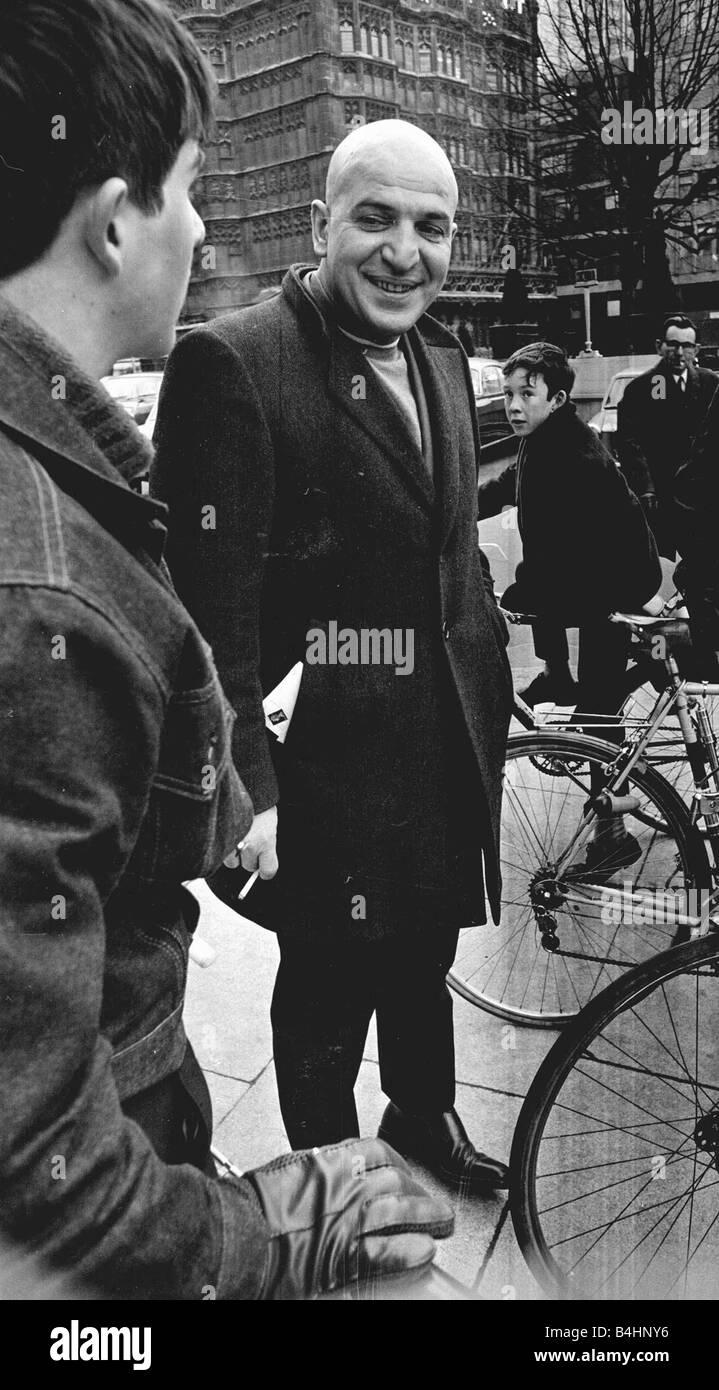 Actor Telly Savalas surrounded by young fans with bikes during walk in London with wife Marilynn Gardner February 1968 1960s Stock Photo