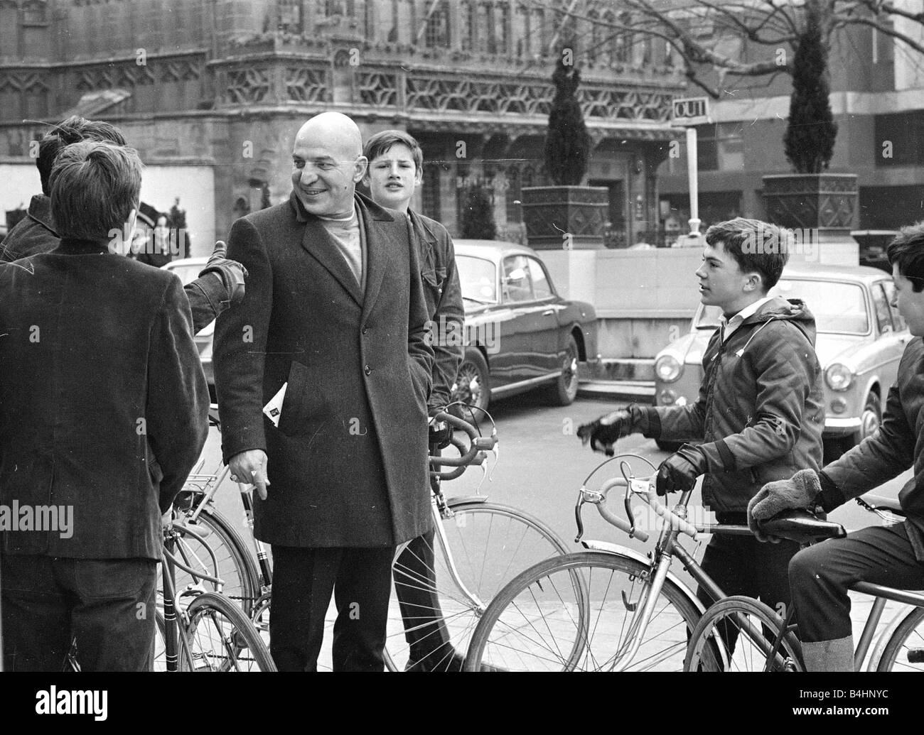 Actor Telly Savalas surrounded by young fans with bikes during a walk in London with his wife February 1968 1960s Mirrorpix Stock Photo