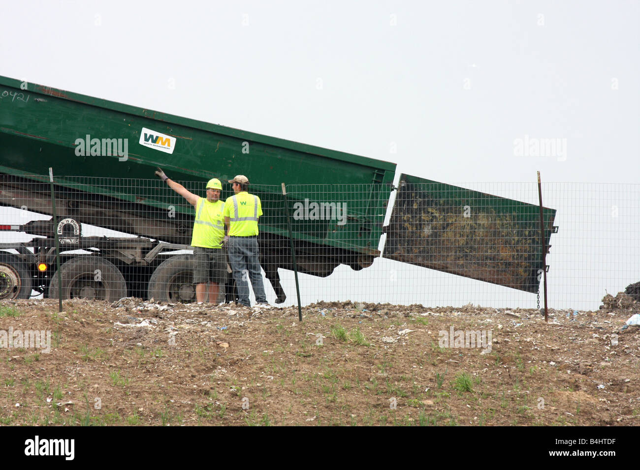 Waste Management Landfill workers with a backhoe placing dirt on trash
