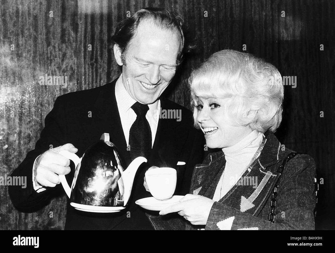 Actor Gordon Jackson pours tea for Barbara Windsor 1976 Stock Photo