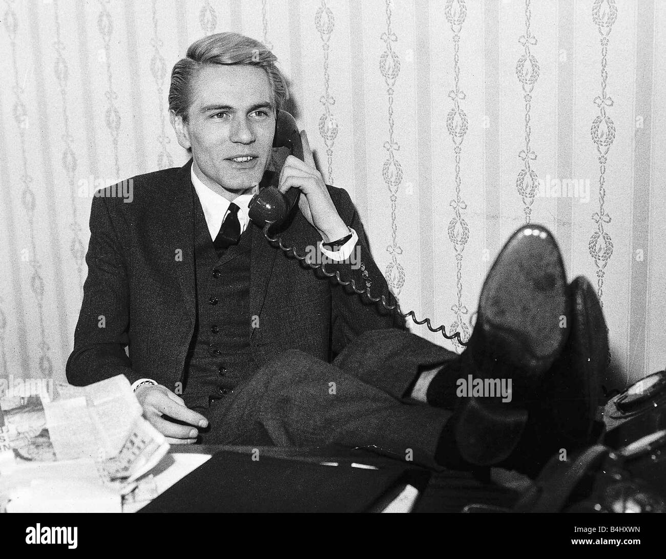 Adam Faith Singer and Actor after cancelling his tour of South Africa because he could not sing in front of mixed audiences sitting with his feet up on his desk on the telephone Stock Photo