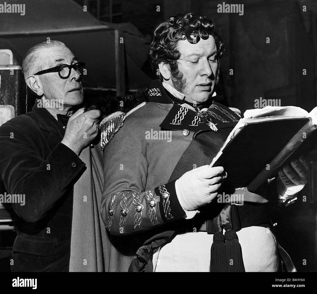 Peter Ustinov actor as King George IV during break in filming at Elstree studios with the wardrobe master holding his cloak February 1954 Stock Photo
