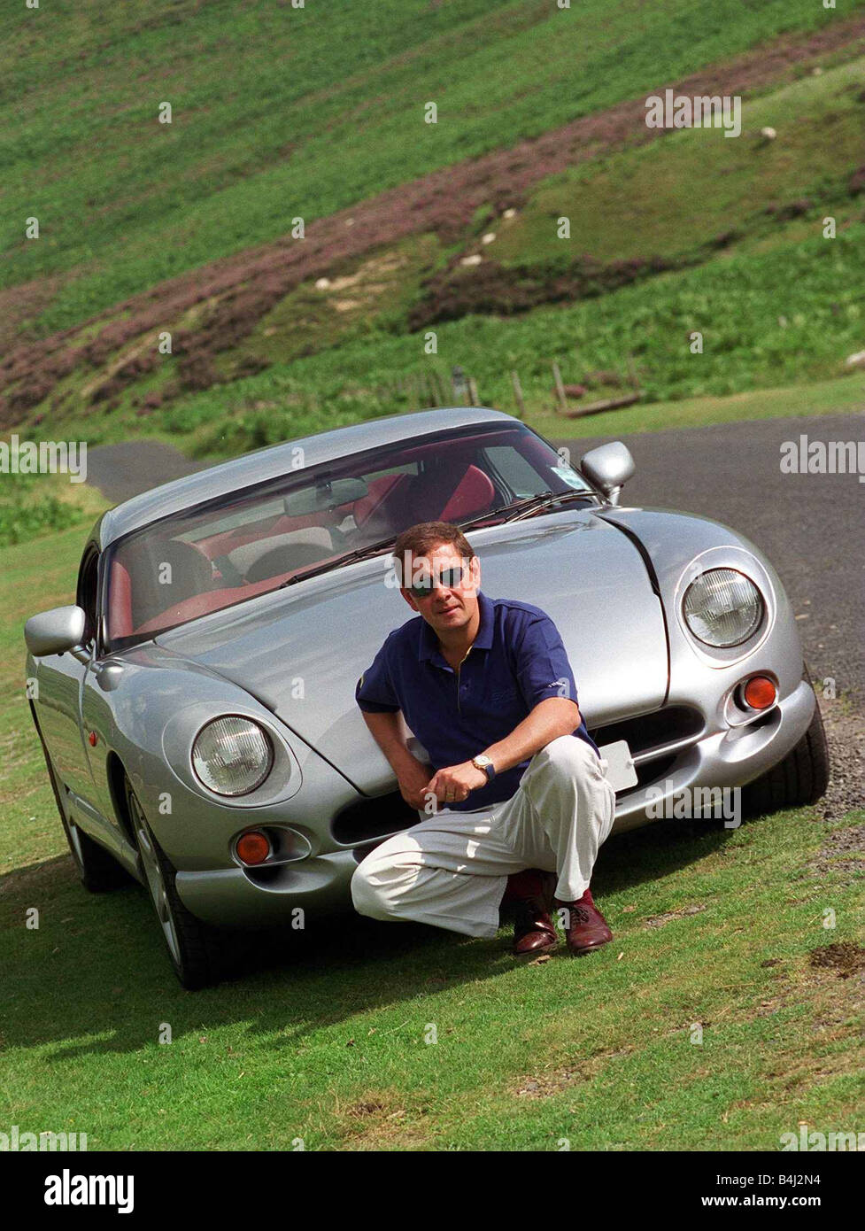 John Clelland sitting in front of a silver grey TVR Cerbera car August 1997 Stock Photo