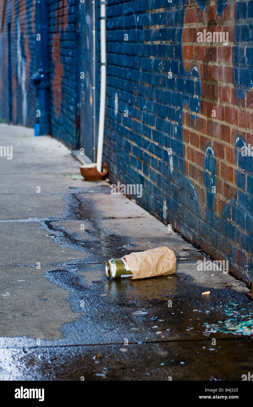 Beer can and a puddle in a dark alley with Graffiti Stock Photo