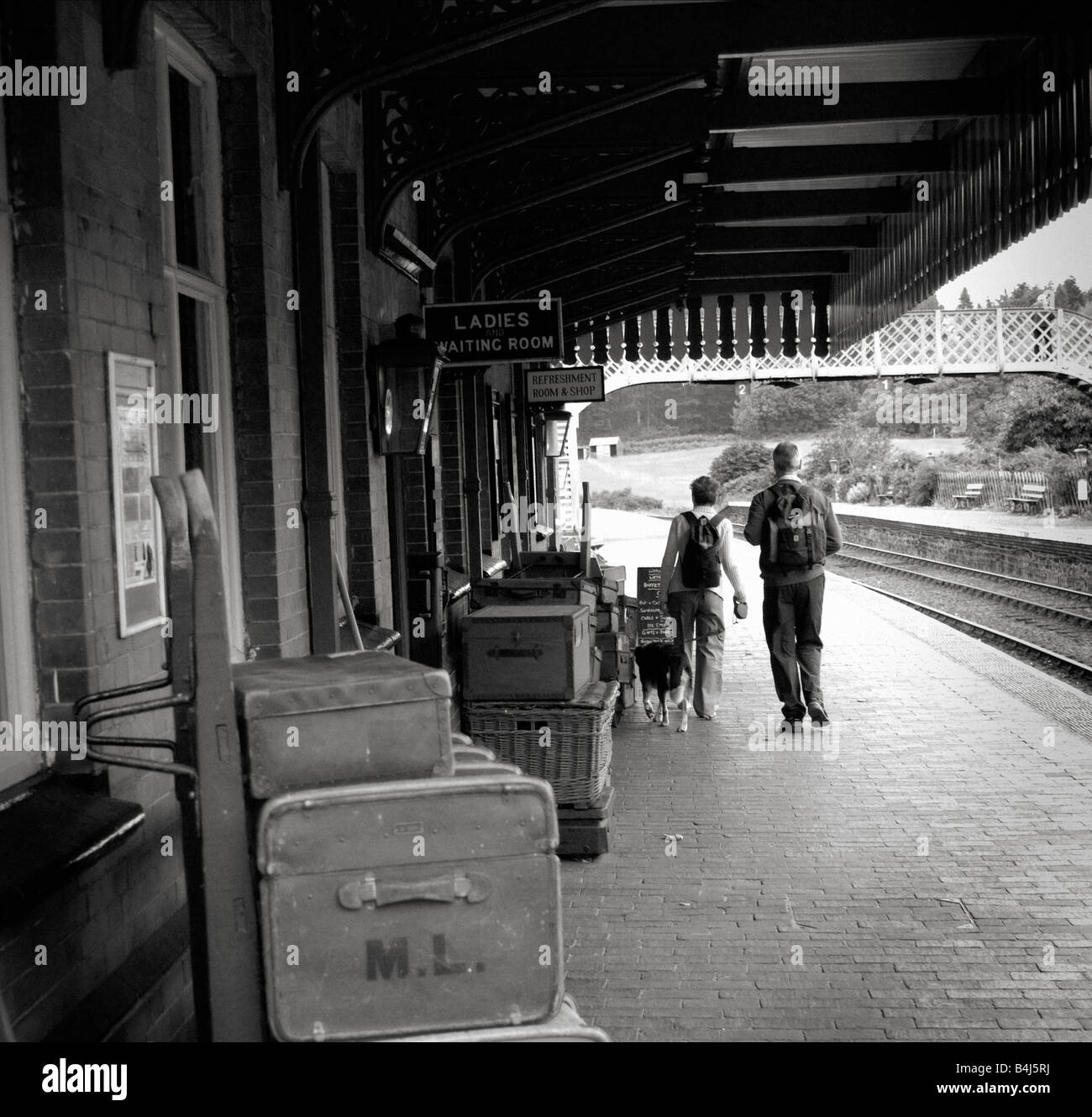 man woman and dog walking on Weybourne railway station platform Norfolk Stock Photo