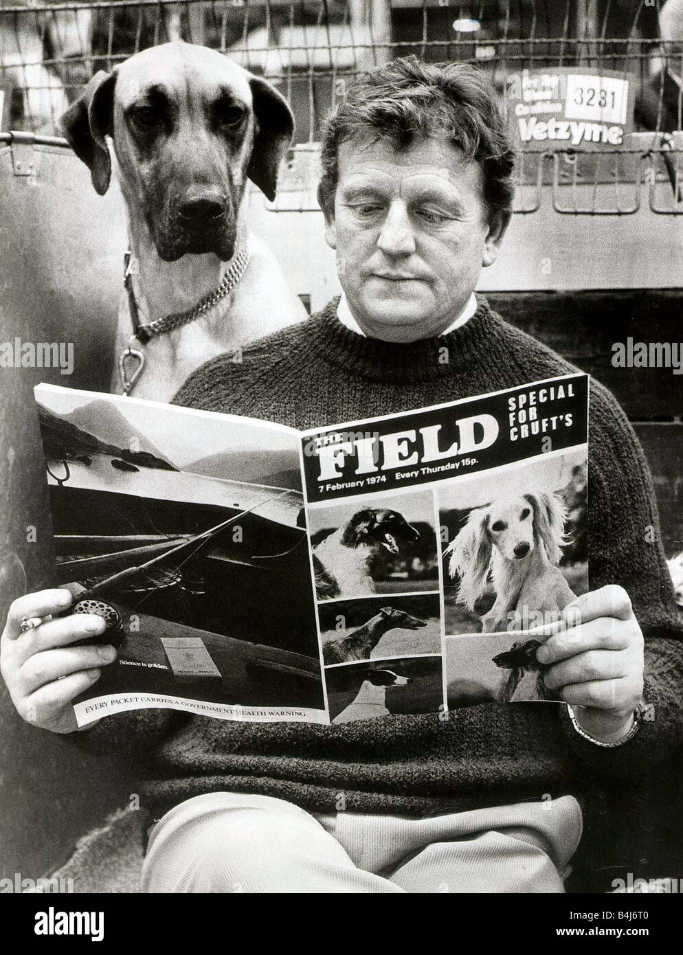 Crufts Dog show opened this morning in Olympia London Competitor Thomas Humphrey checks the form with his mut Liza the Great Dane A man reading with a dog looking over shoulder Field Magazine February 1974 Stock Photo
