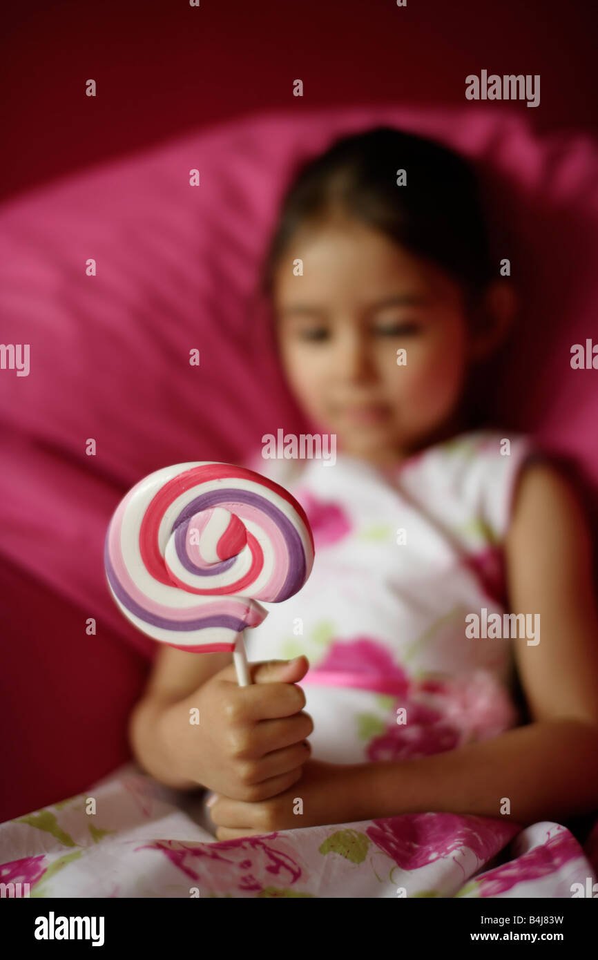 Girl 5 on pink bean bag with lollipop Stock Photo