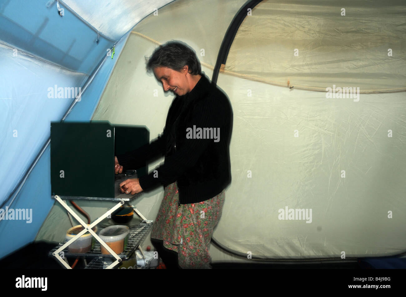 A woman cooking in her tent during a storm Stock Photo