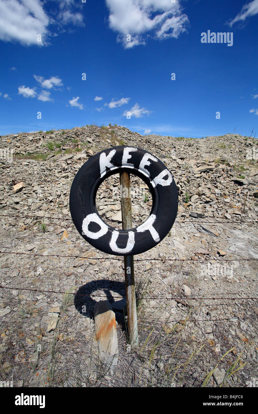 Barbed wire fence with tire sign painted keep out near Pincher Creek