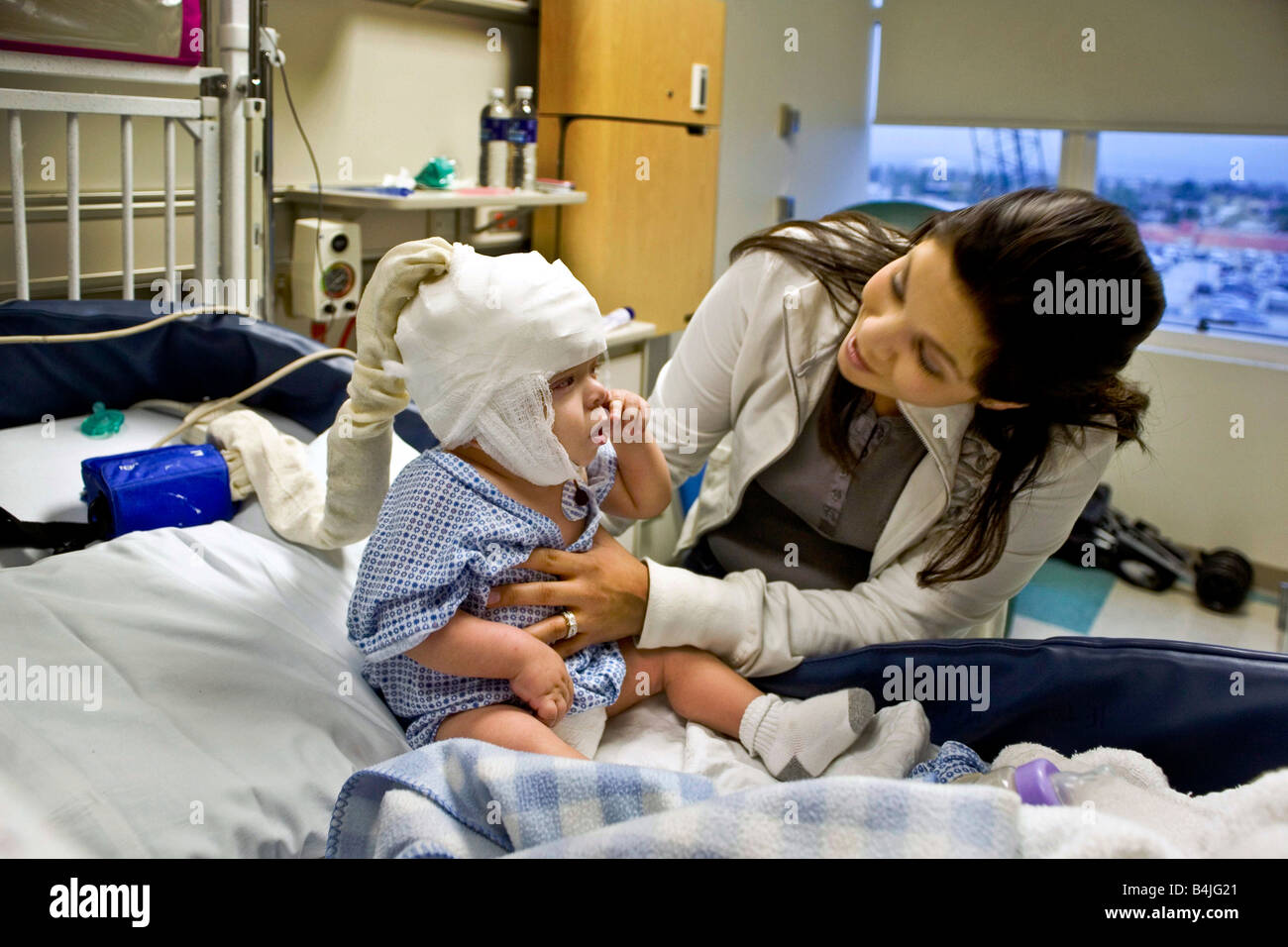 In a California hospital a mother cares for her infant son suffering from spinal bifida Note condition monitoring EEG cap Stock Photo