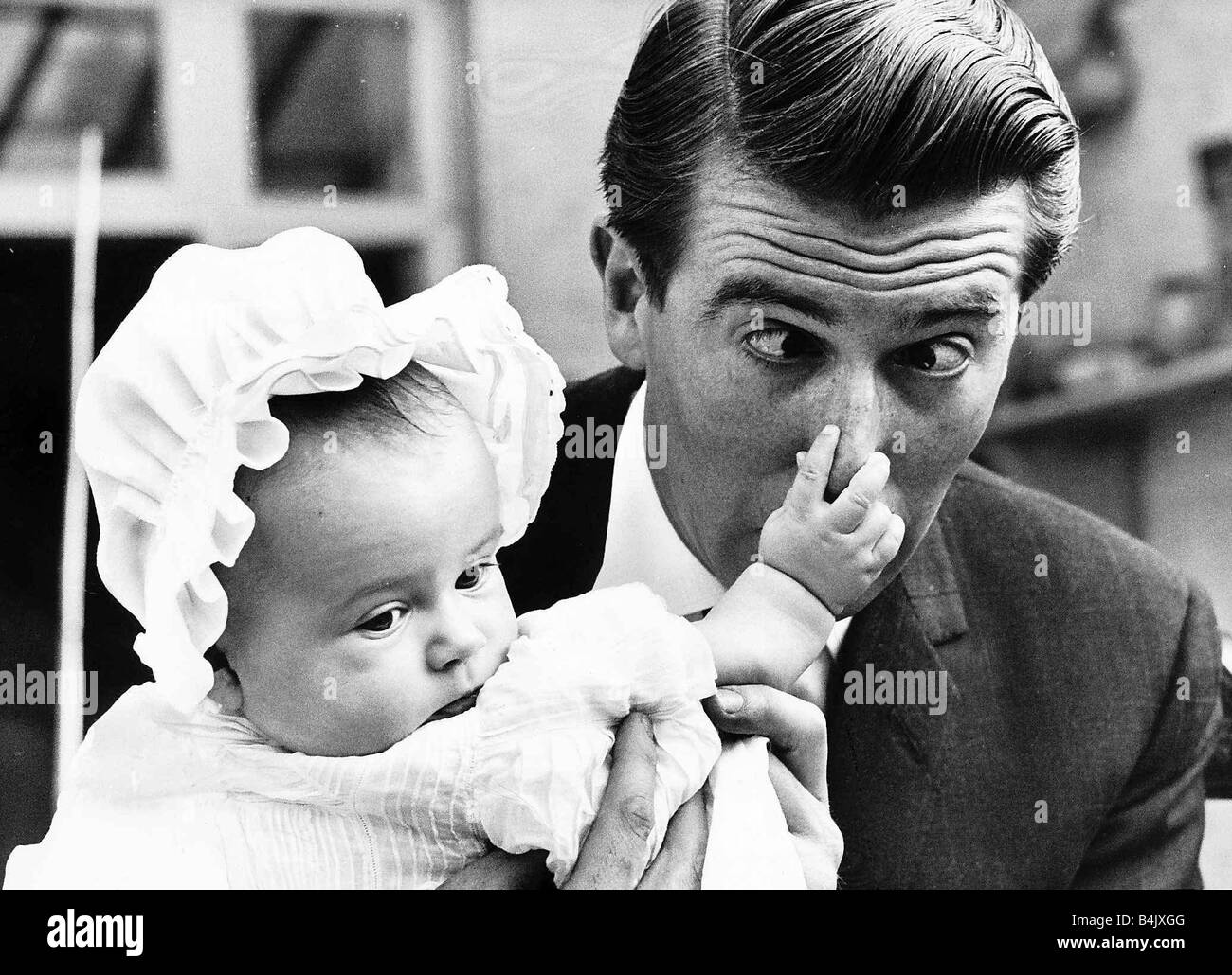 Leslie Crowther actor and TV presenter his 4th baby daughter holding his nose Stock Photo
