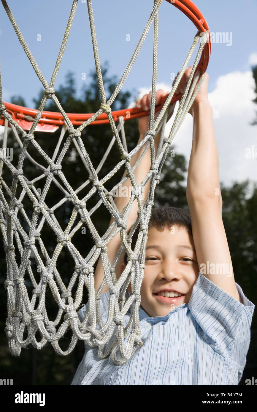 Asian boy hanging from basketball hoop Stock Photo Alamy