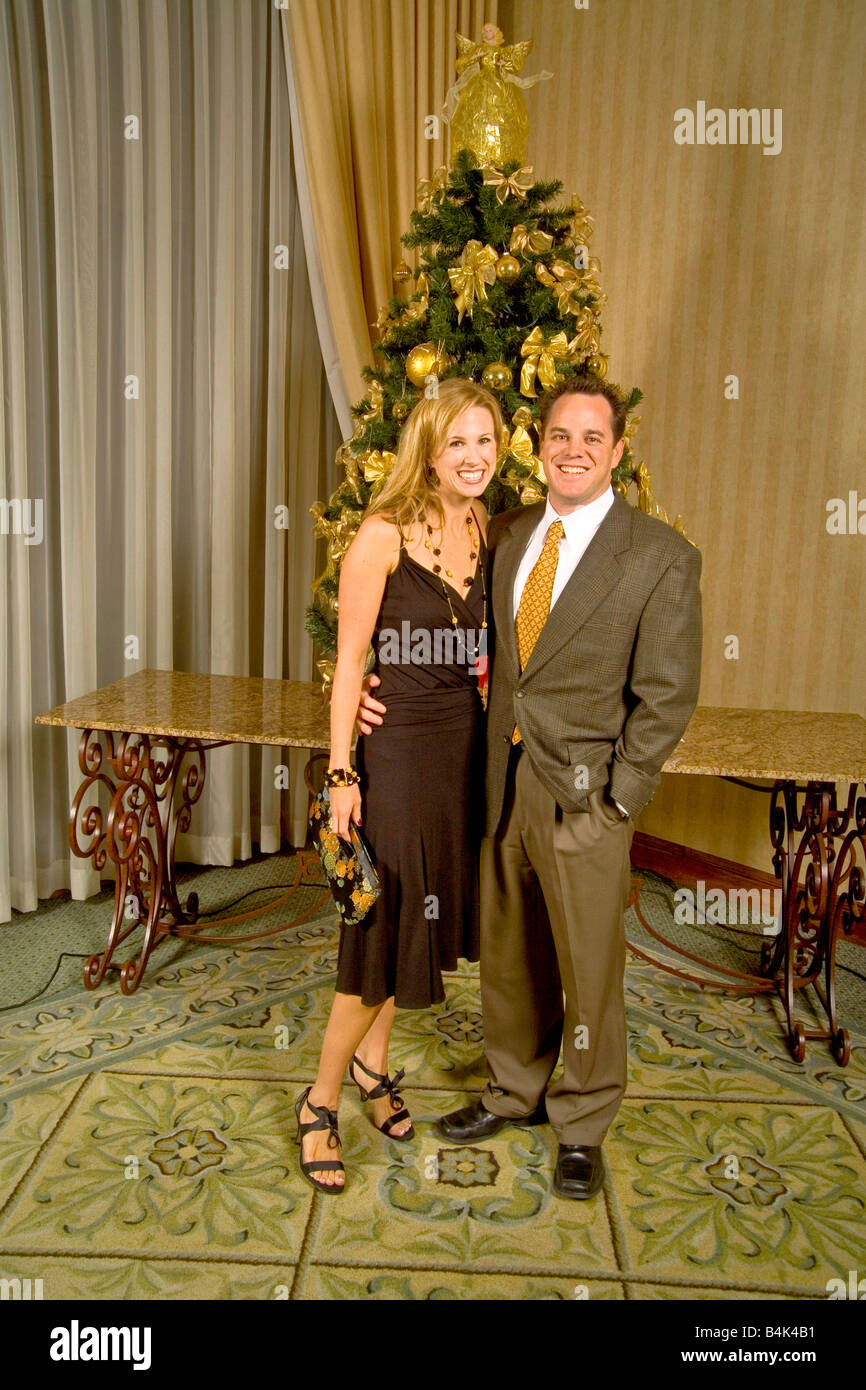 A couple pose for a formal picture in front of a Christmas tree at a holiday party in California MODEL RELEASE Stock Photo