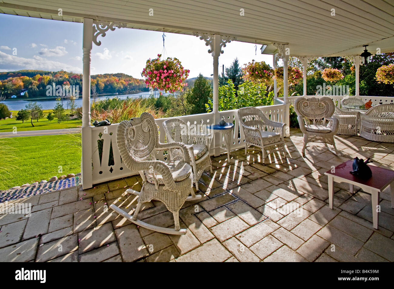 Late afternoon sun shines on old fashion wickerwork chairs on the porch of a home in rural Michigan Note autumn colors Stock Photo