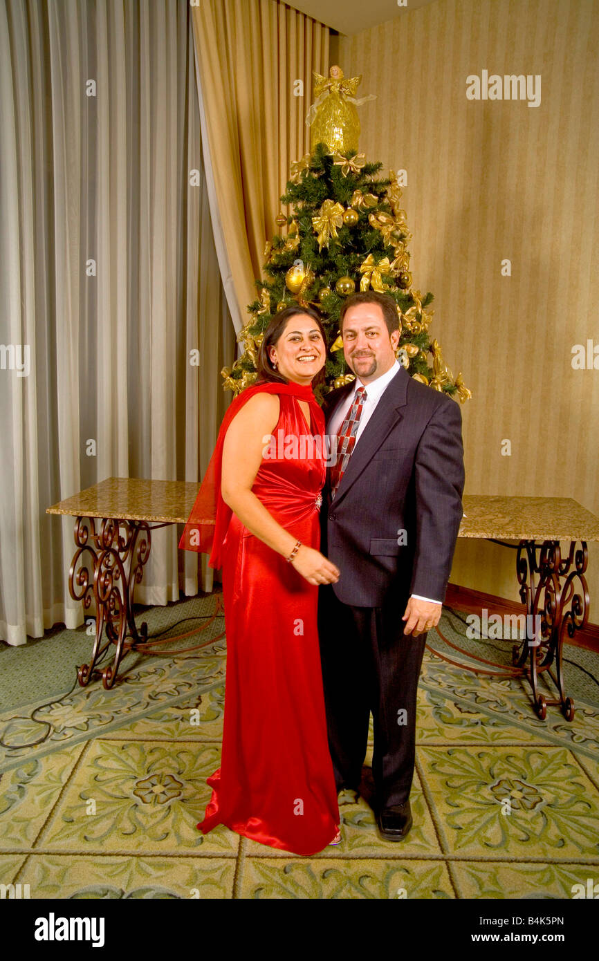 A couple pose for a formal picture in front of a Christmas tree at a holiday party in California MODEL RELEASE Stock Photo