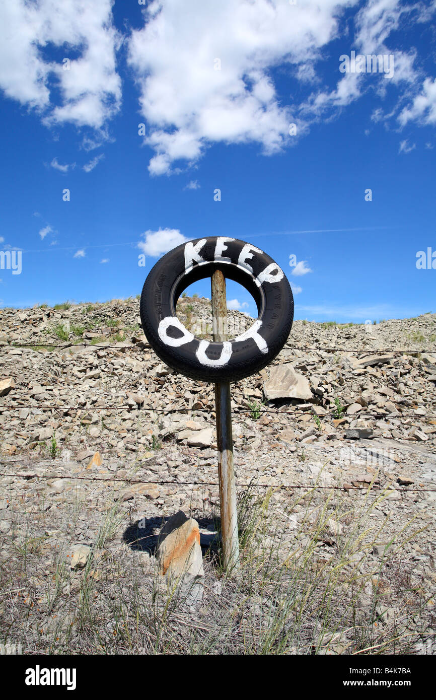 Barbed wire fence with tire sign painted keep out near Pincher Creek