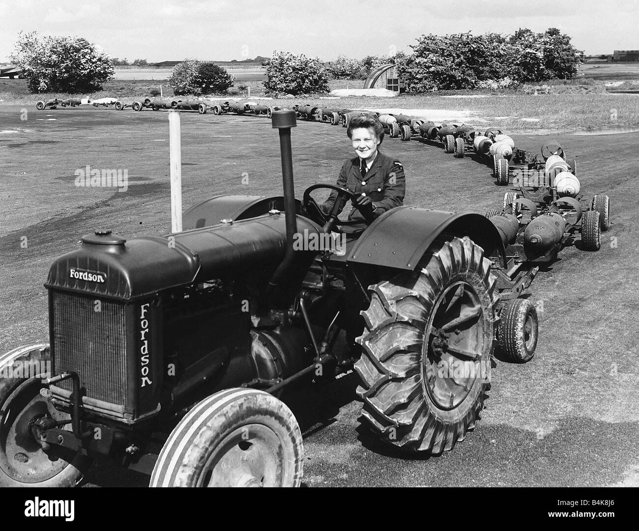 A WAAF driving a tractor pulling a load of 1 000lb bombs on an RAF base