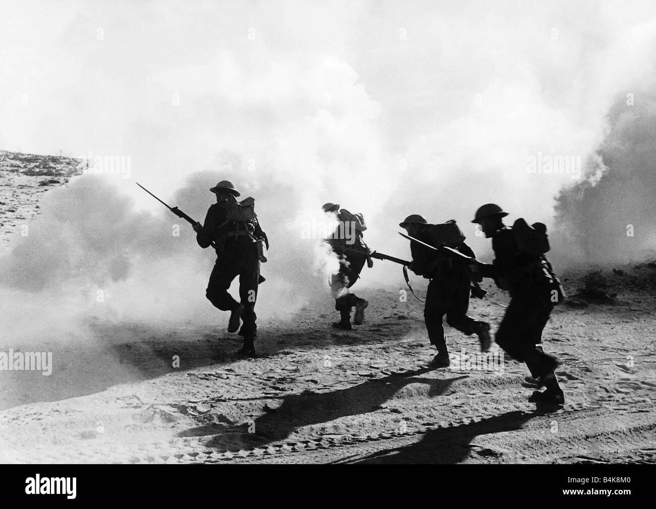 British troops with fixed bayonets advance through a smoke screen in the Western Desert in Libya WW2 Stock Photo