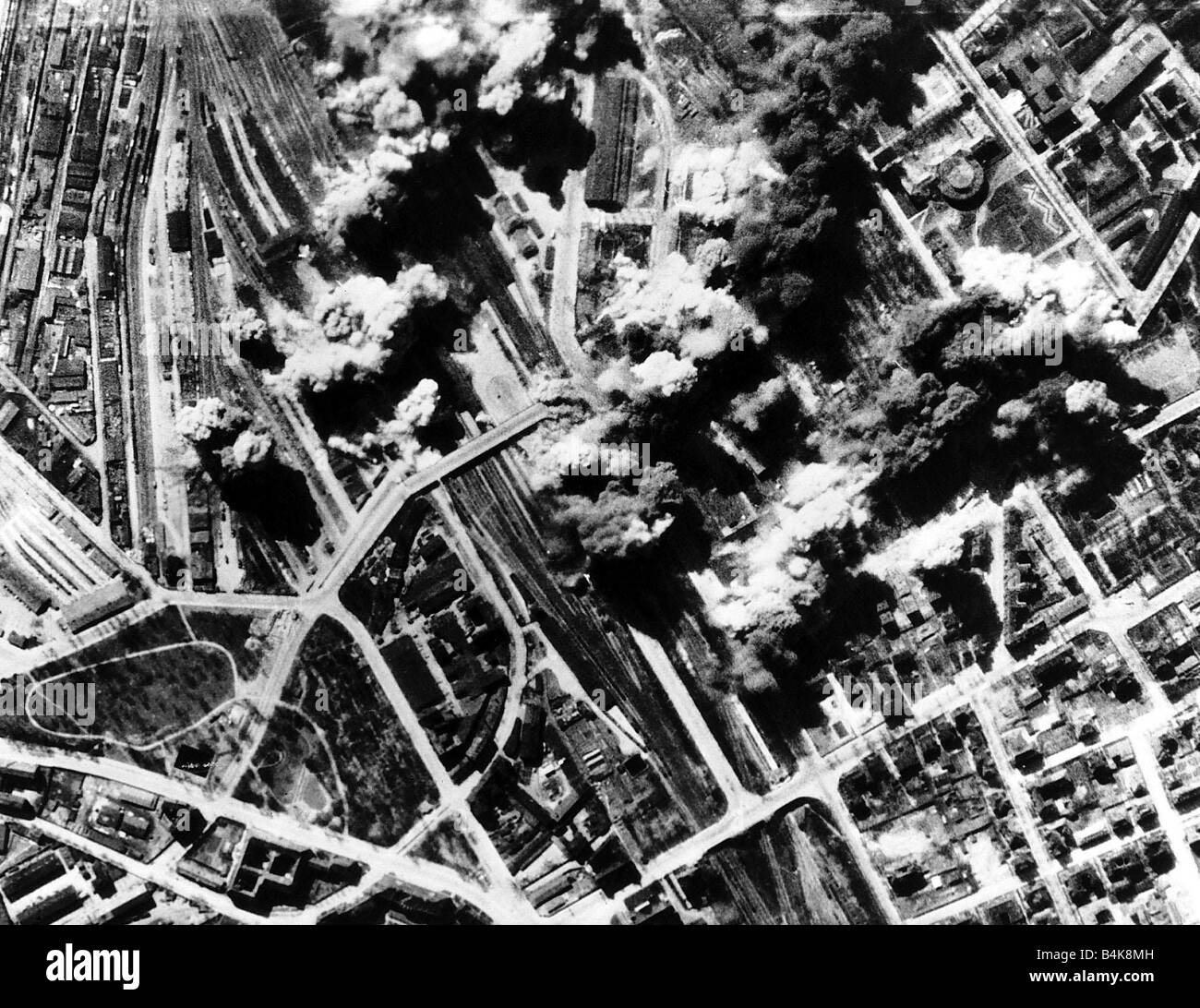 An aircraft factory producing FW 190 fuselages and a railway marsheliing yards at Poznam in Poland are hit by bombs dropped by a squadron of AAF B17 Flying Fortresses during WW2 1944 Stock Photo