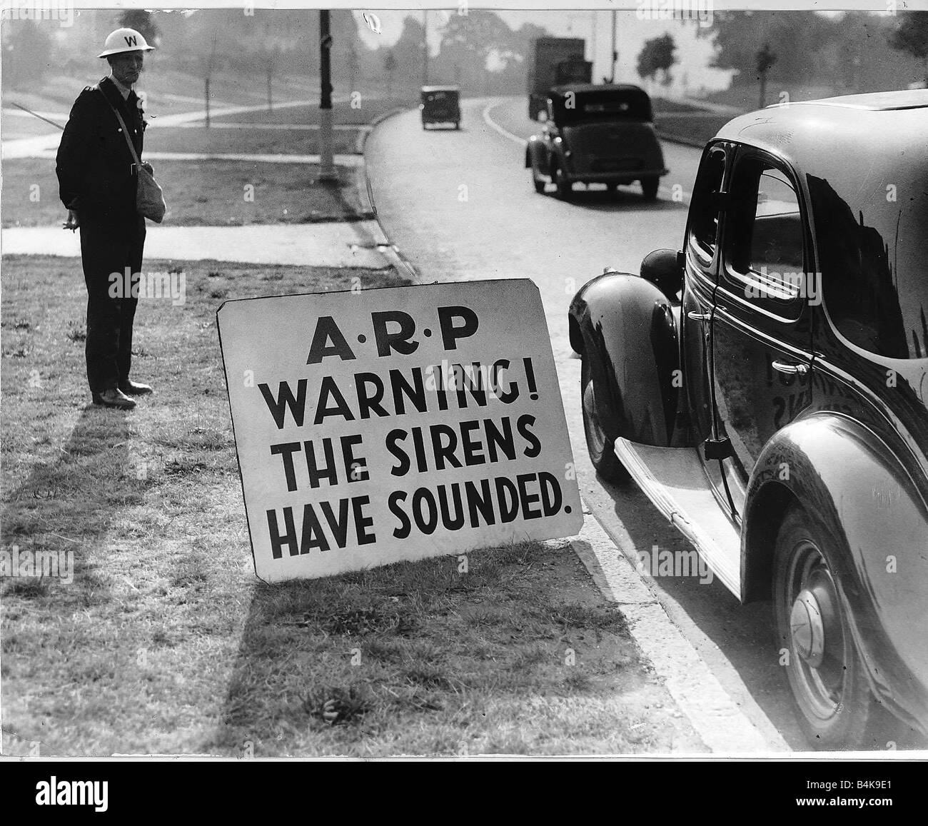 WW2 Air raid warden by road side Sept 40 warning notice for road users Stock Photo