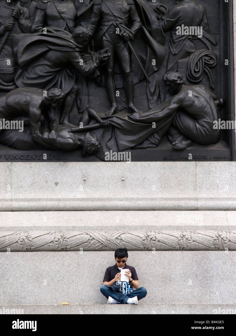 Tourist eating lunch at the base of Nelsons Column Trafalgar Square London Stock Photo