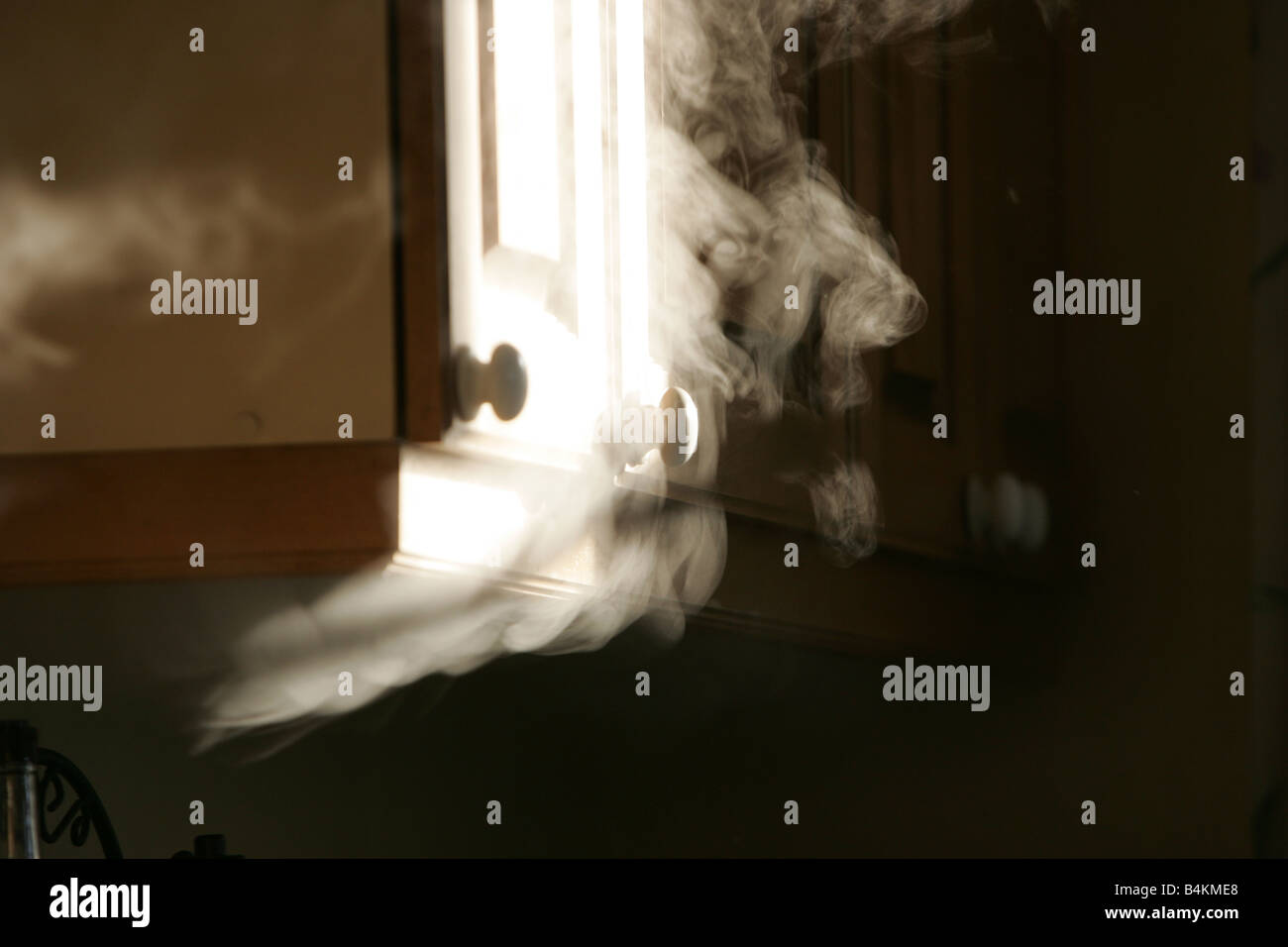 Smoke bellows out from under a cupboard Stock Photo