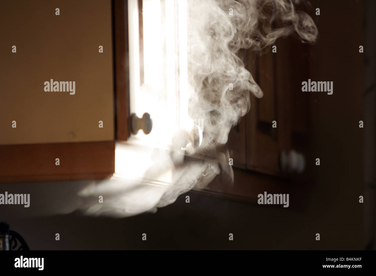 Smoke bellows out from under a cupboard Stock Photo