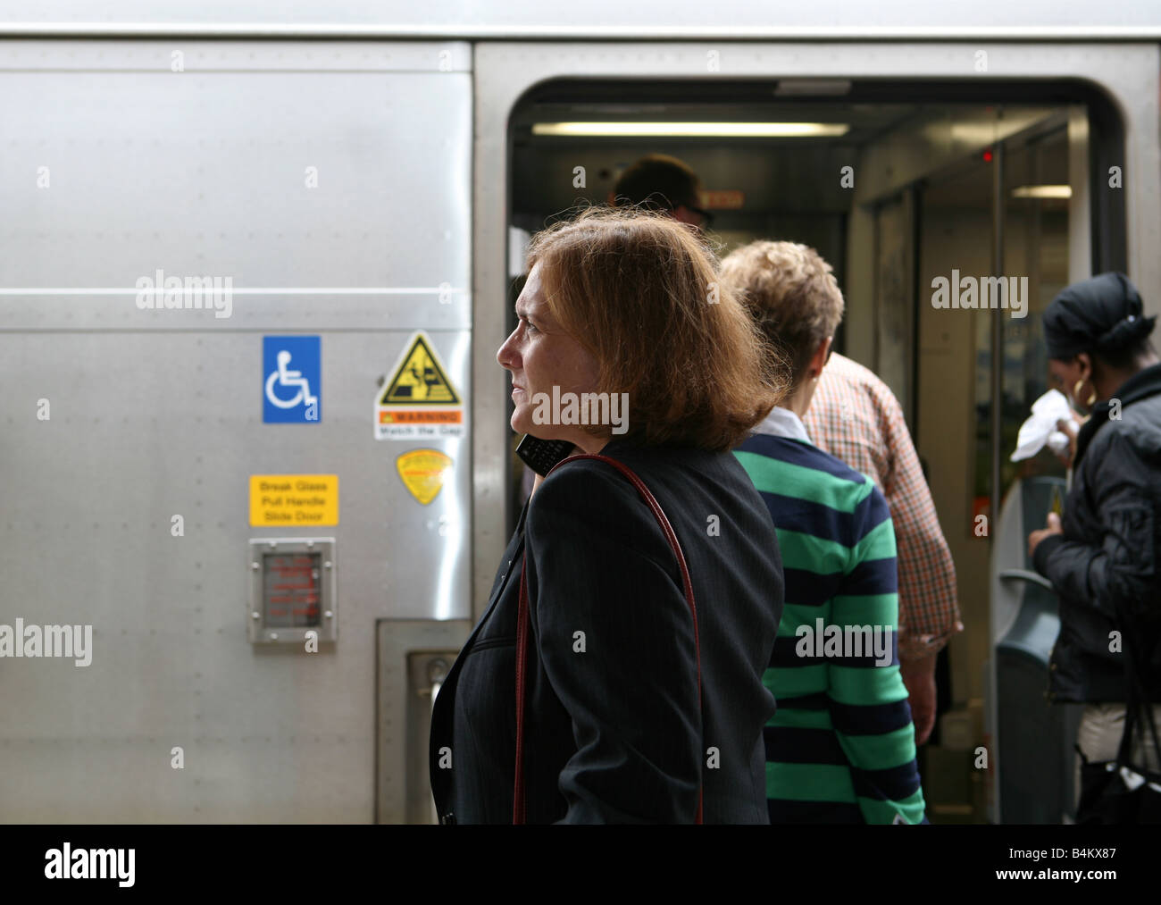 Commuting businesswoman keeps busy while awaiting the arrival of her train Stock Photo