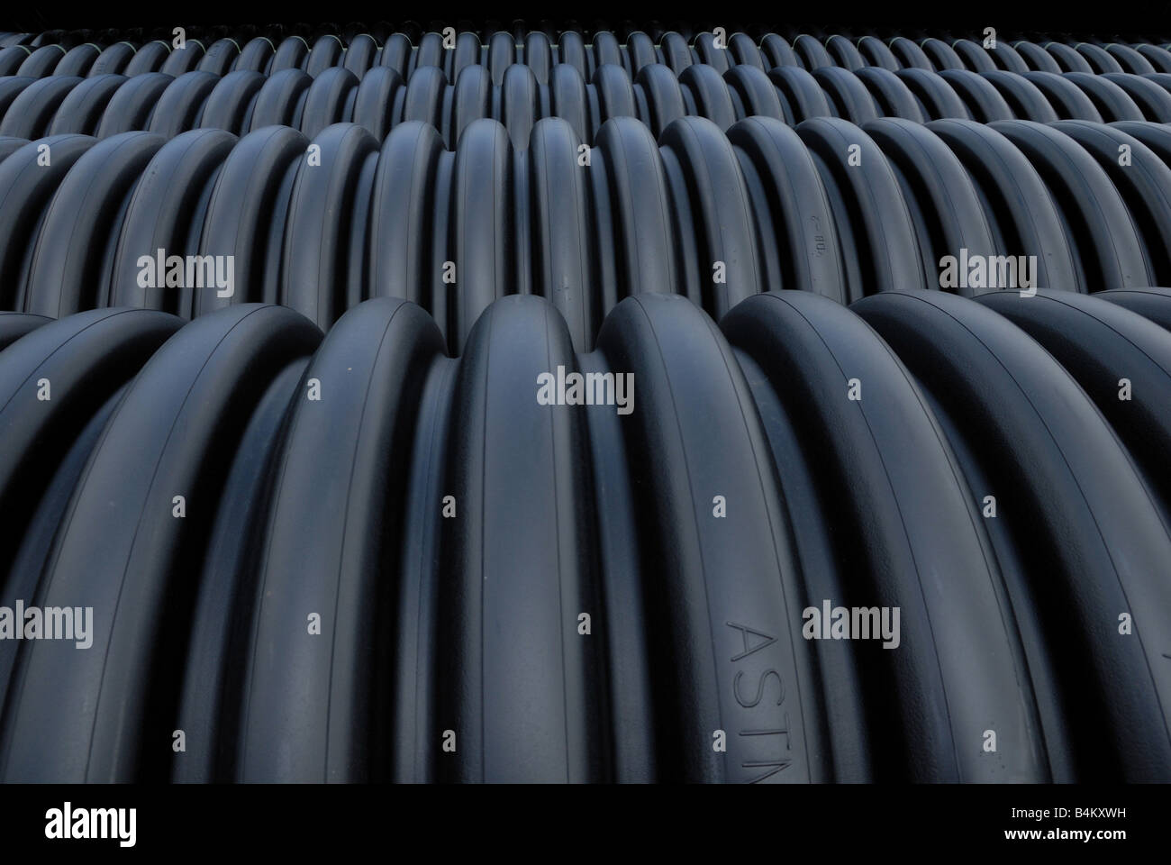 Rows of black ribbed tubes are building materials on a construction site. Stock Photo