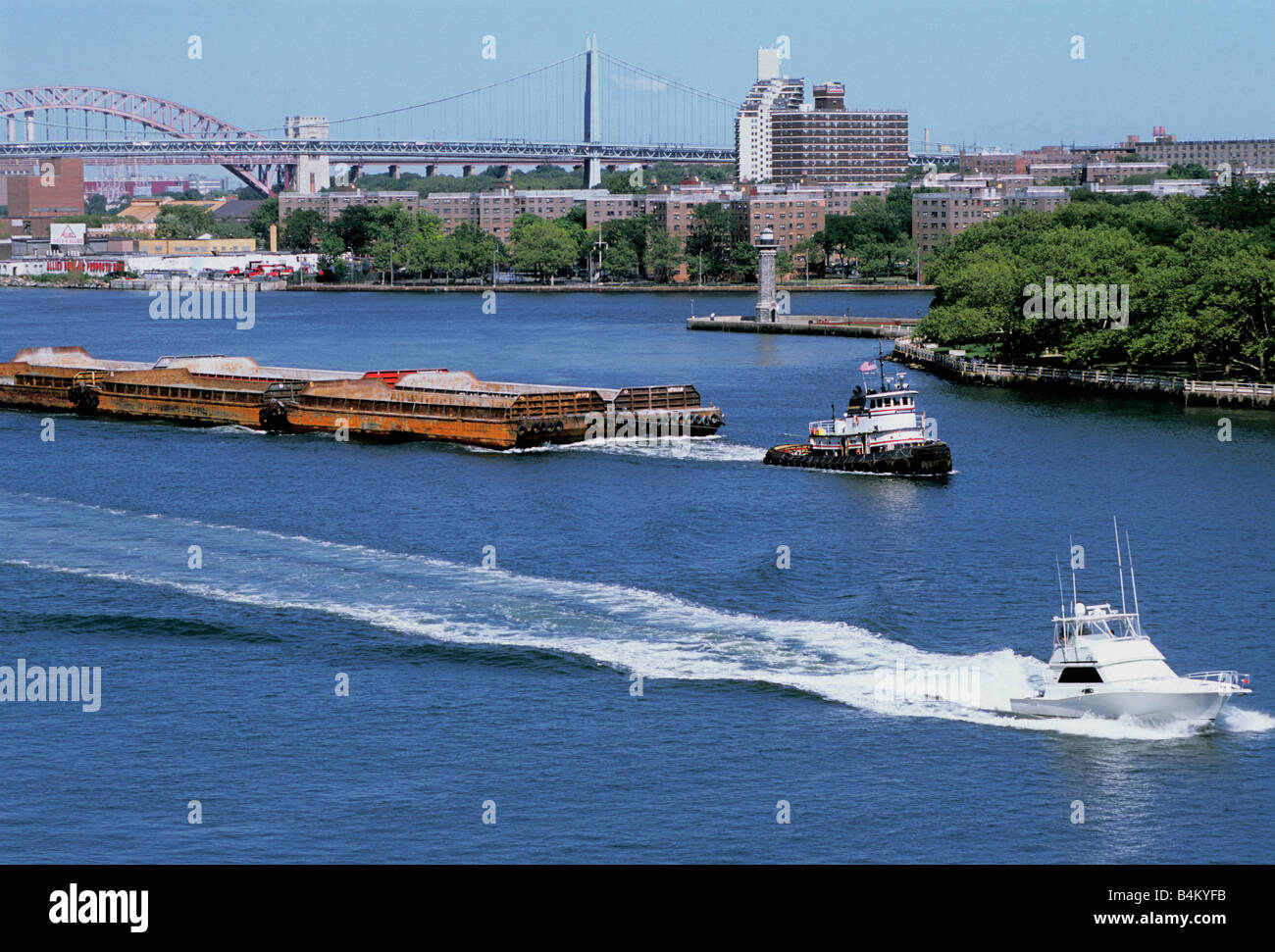 Tugboat, barge scow, motor boat, Roosevelt Island, Lighthouse Park, Robert F Kennedy Bridge, and Hell Gate Bridge. River traffic. MTA, USA Stock Photo