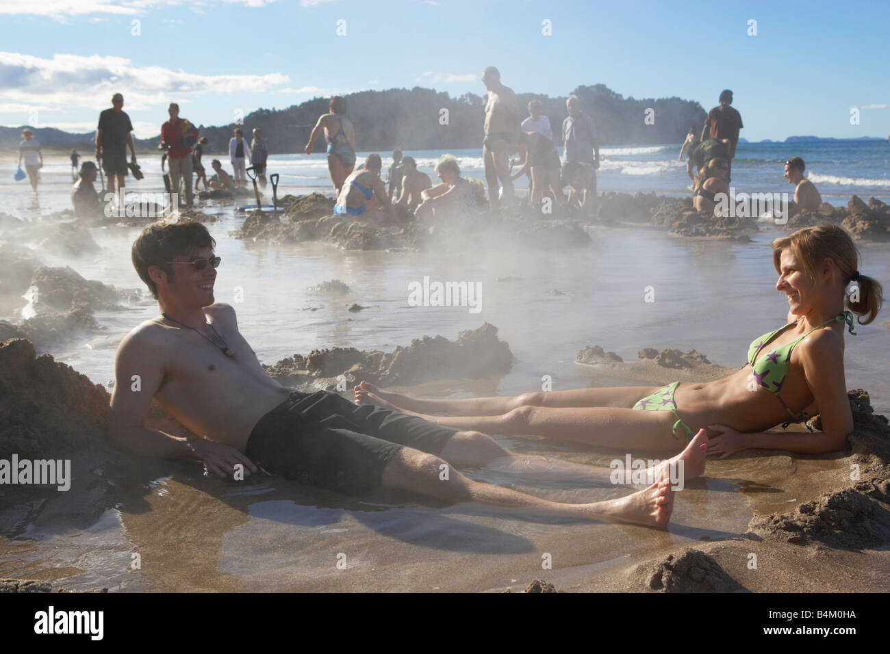 Couple lying in hot water pool they have dug on Hot Water Beach Coromandel  North Island New Zealand Stock Photo - Alamy