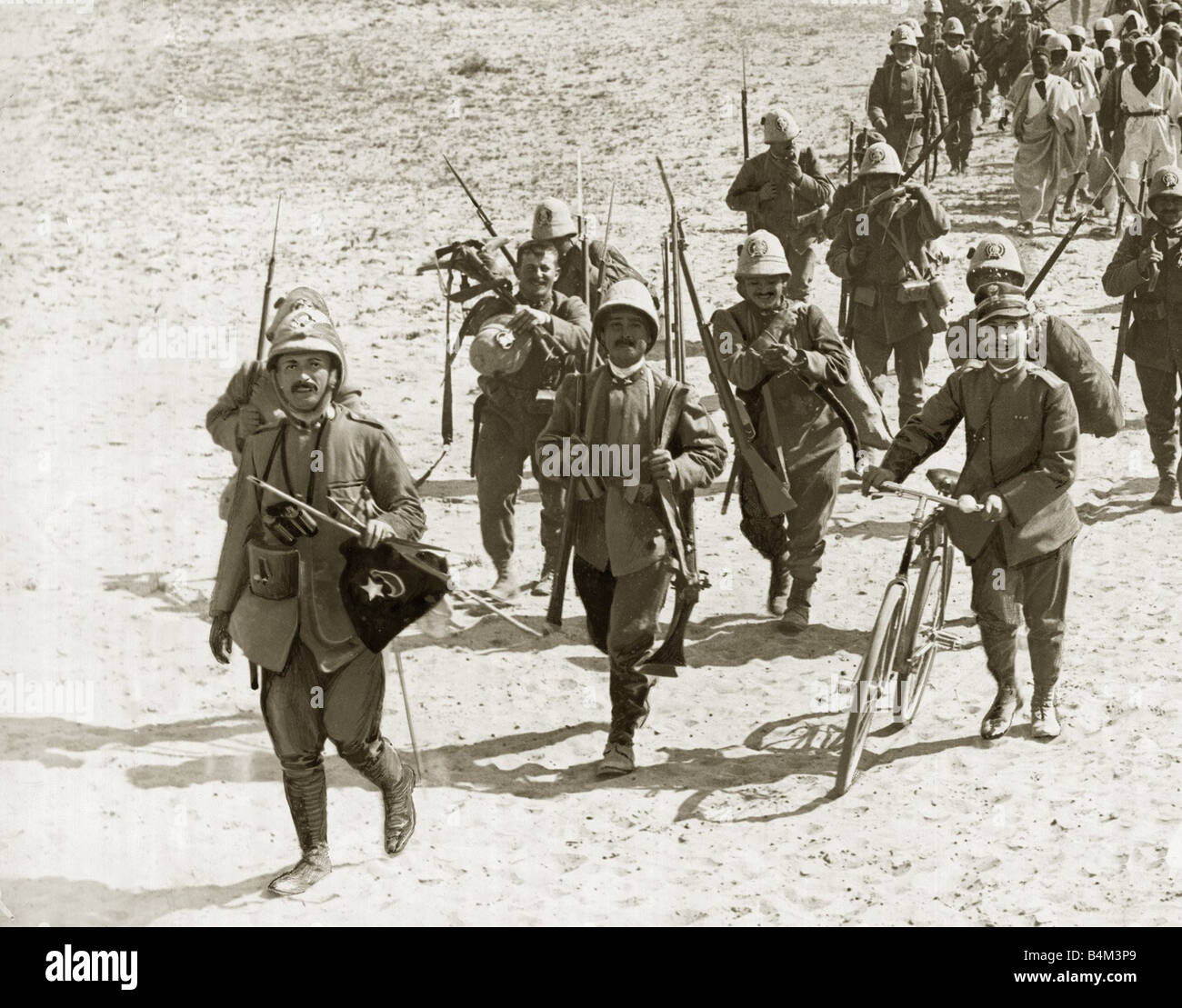 Turco Italian War Italian officers lead a column of soldiers escorting arab prisoners The lead officer holds a captured turkish Stock Photo