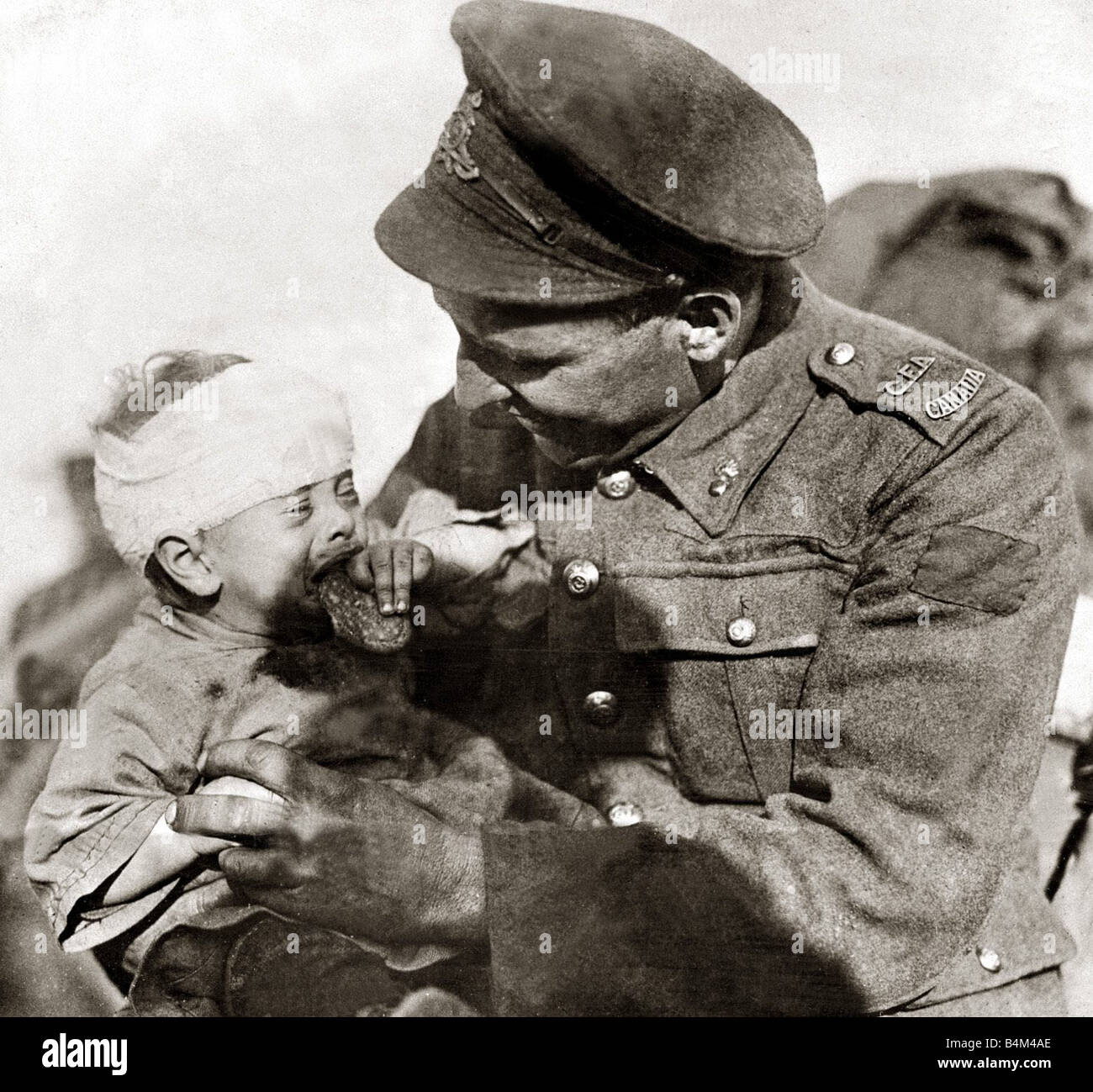 A Canadian artillery man tries to amuse a little Belian baby The mother was killed and the child who was in her arms was wounded by a german shell kindness hope love soldier Stock Photo