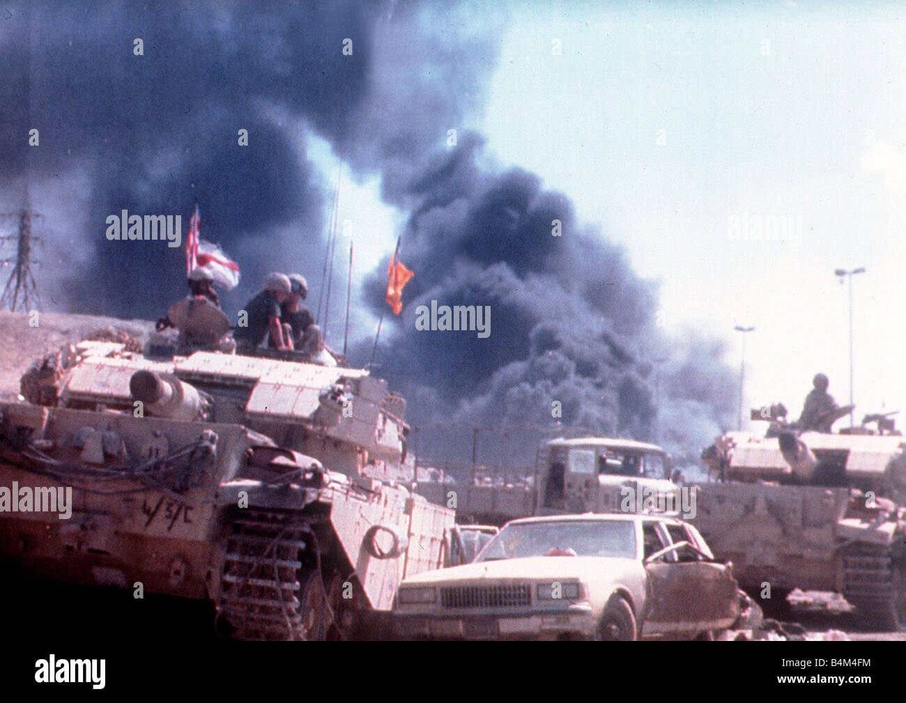 British army engineers use armoured vehicles to clear the road to Kuwait City during Operation Desert Storm Seen in the background is one of over four hundred oil wells set alight by retreating Iraqi forces Stock Photo