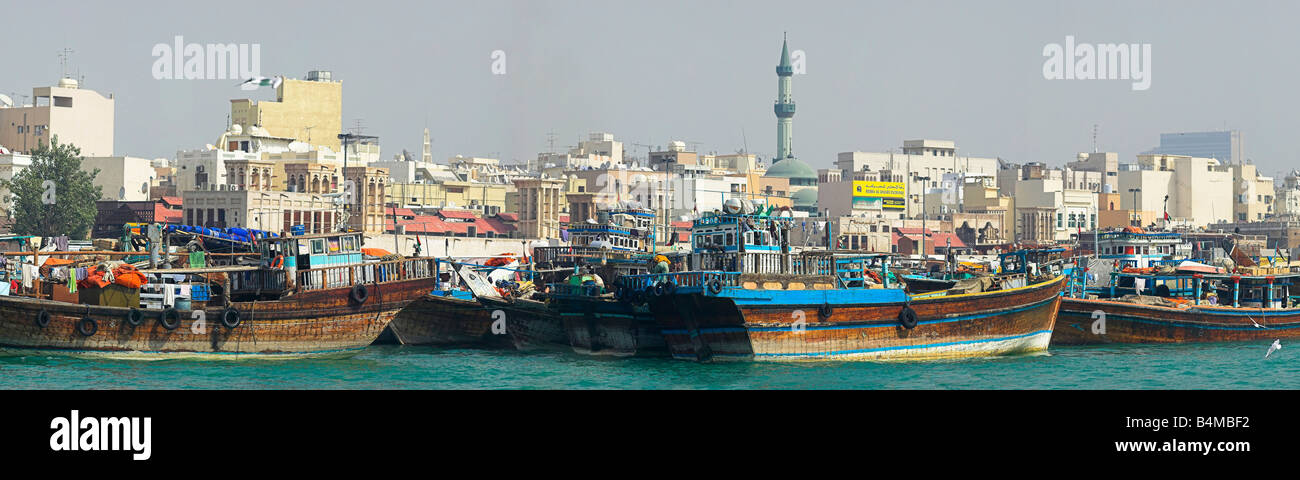 Panorama of Traditional freight boats Dhows on The Creek, Dubai with old city and souks in background Stock Photo