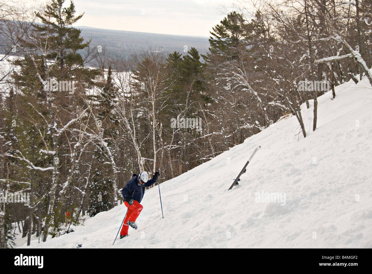 A skier walks back up to his skis after falling on a steep slope at Mount Bohemia ski resort in Michigans Upper Peninsula Stock Photo