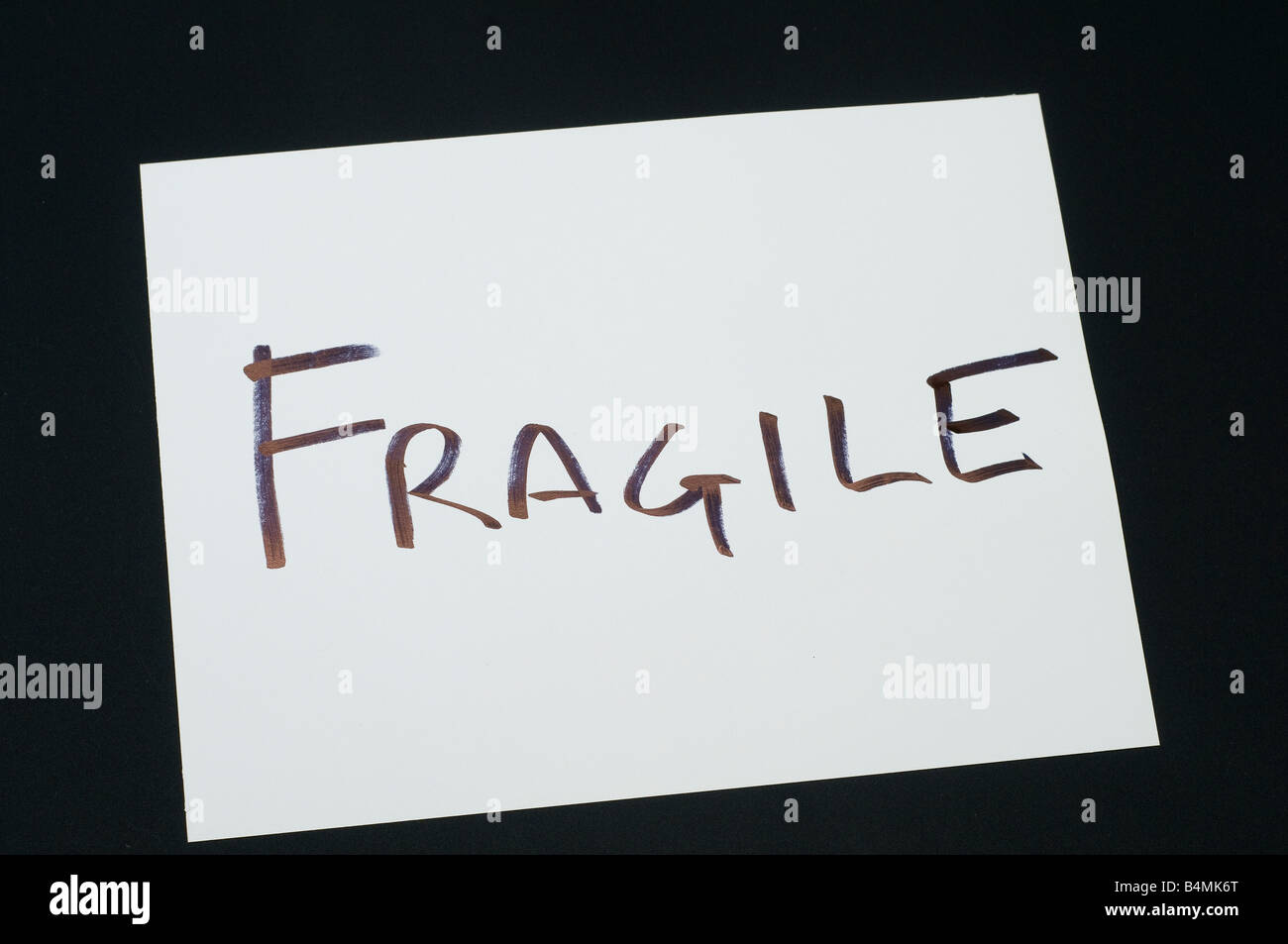 a note with the word Fragile on a black background Stock Photo