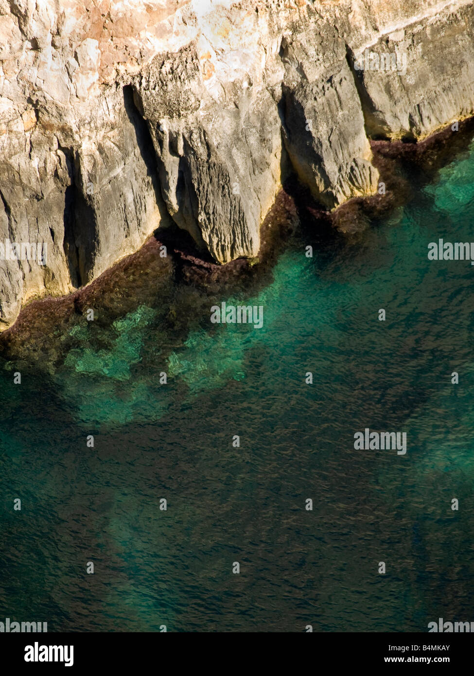Deep clear emerald sea next to coastal cliff Stock Photo
