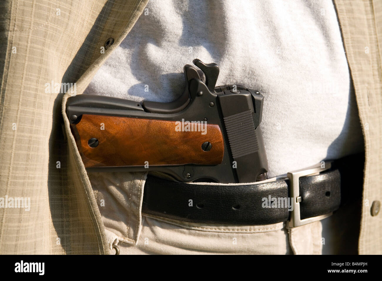 A handgun sits in a man's belt. Stock Photo